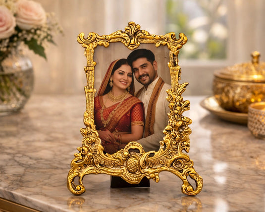 Decorative gold frame with a couple's photo on a marble surface with flowers and a candle in the background