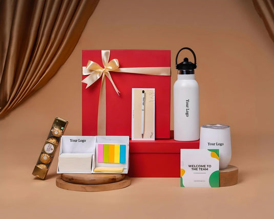 A gift box named 'Rise & Grind' containing an assortment of items including a white vacuum flask, a gold-colored watch, a multicolor pen, and yellow sticky notes, all displayed on a red surface.