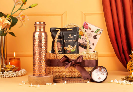 Copper water bottle, wicker basket with snacks, and decorative items on a table with a warm background.